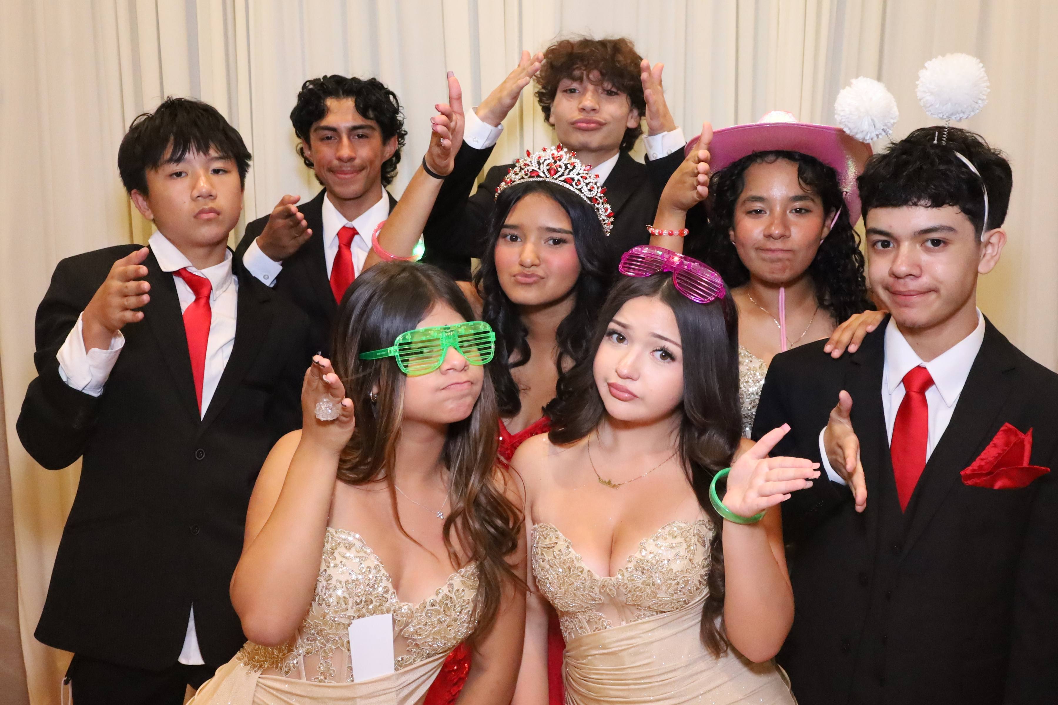 Eight teens at a quinceañera in red ties and gold gowns