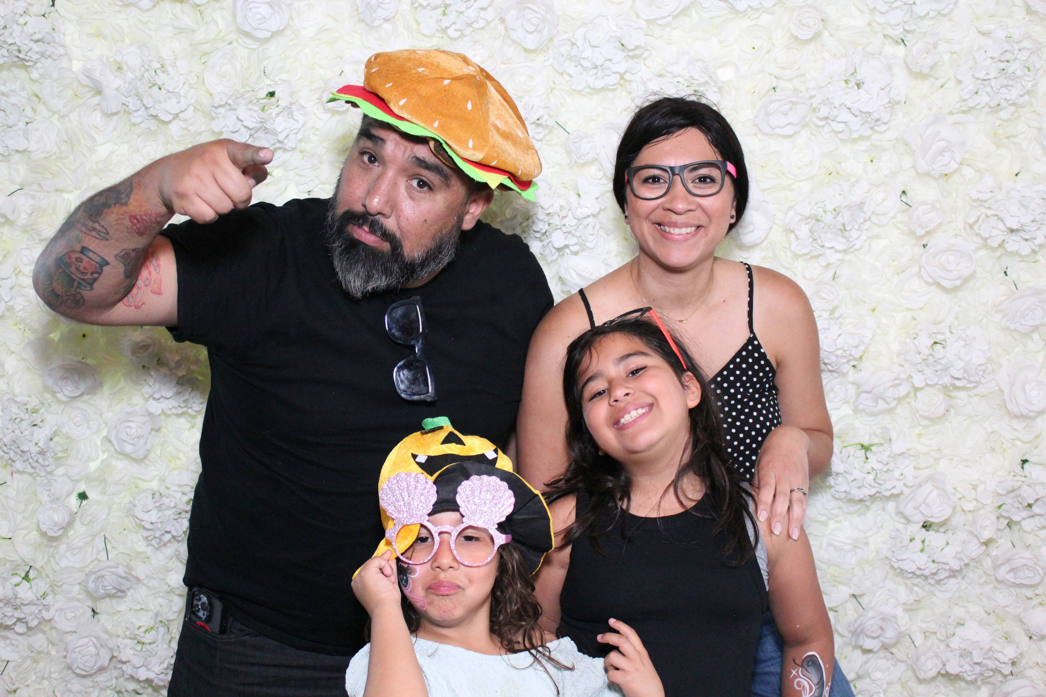 Family of four with fun props on white flower wall